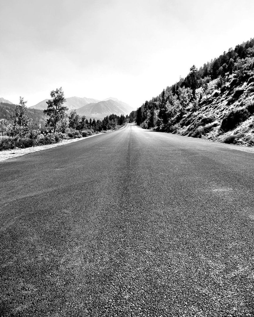A lonely stretch of road cuts through the John Muir Wilderness, framed by rugged pines and distant Sierra peaks — a quiet invitation into the wild.