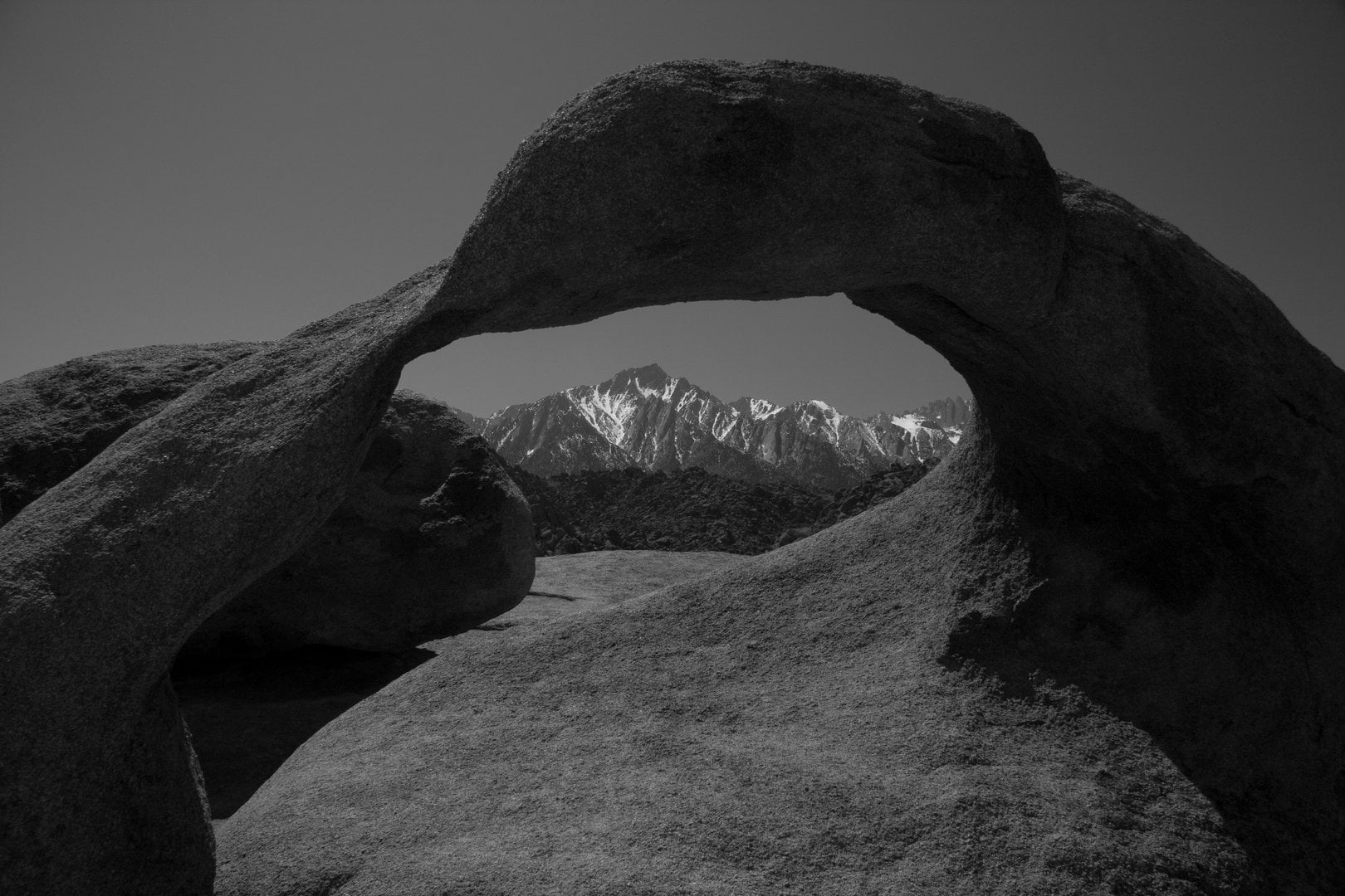 Framed by the natural arch of Whitney Portal, the Sierra peaks rise in quiet strength beyond. The black-and-white tones draw out the contrast between the smooth stone foreground and the rugged, snow-capped mountains — a perfect window into California’s wild heights.